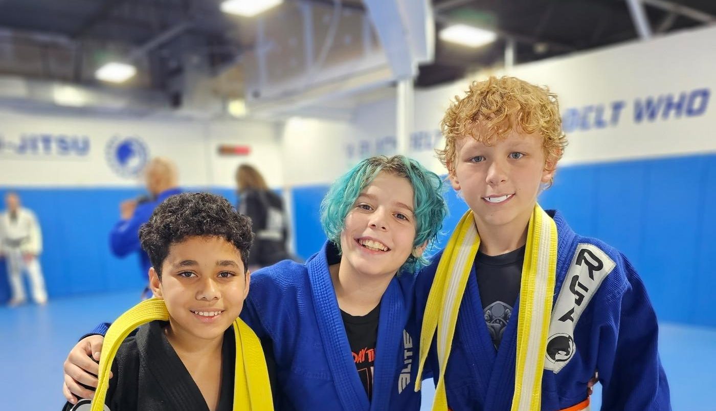 Kids smiling with their new belts on the mat