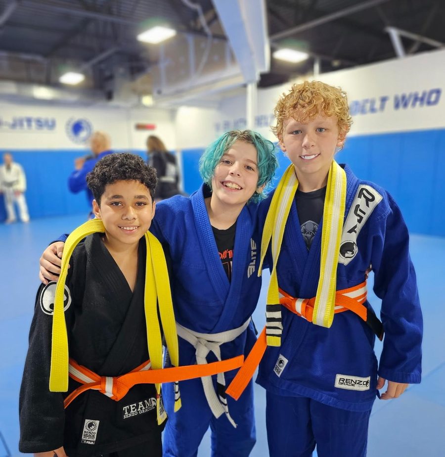 Kids smiling with their new belts on the mat