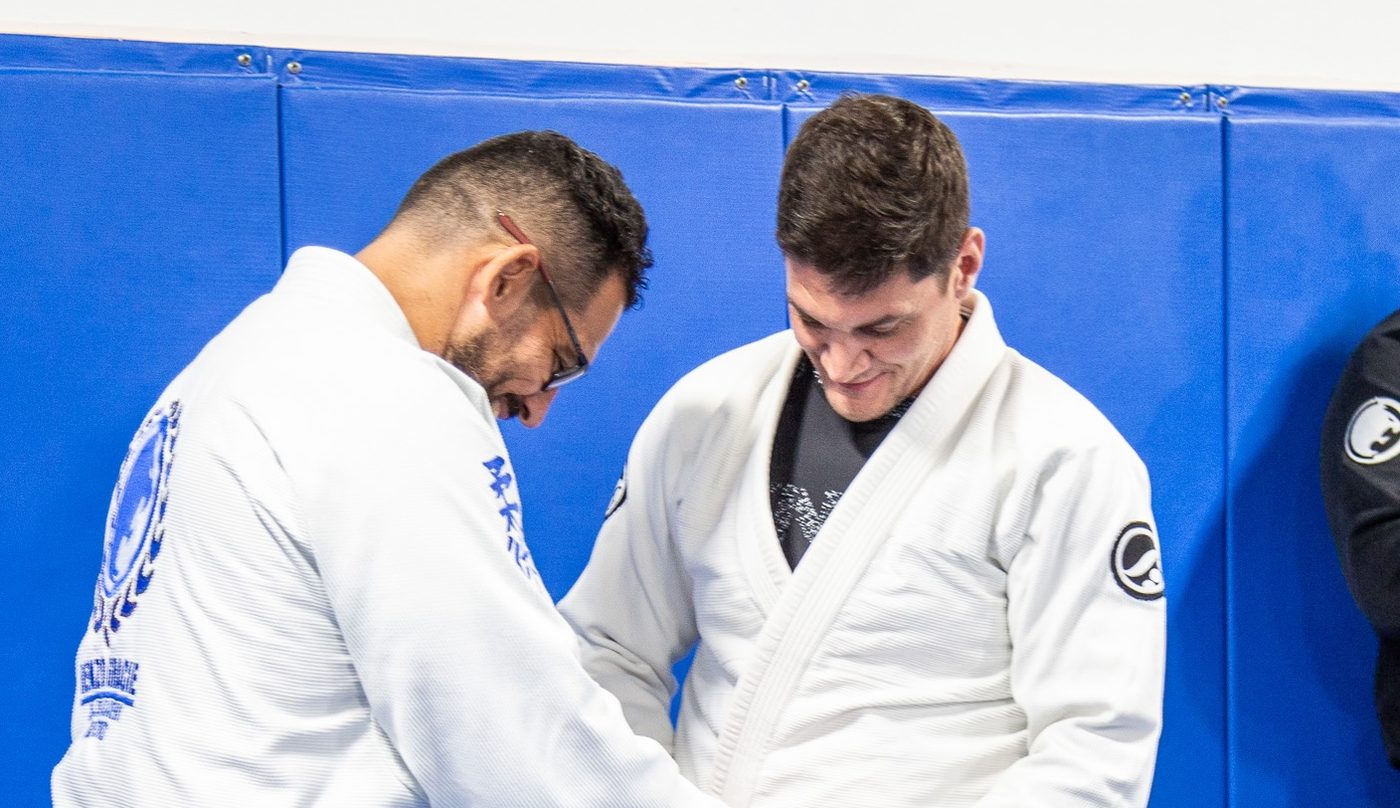 A Renzo Gracie Naples professor tying a new belt on a student at a belt promotion